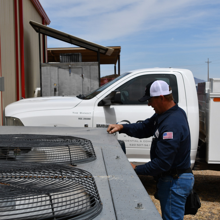 A GNS technician checks a commercial condensing unit beside a GNS truck.